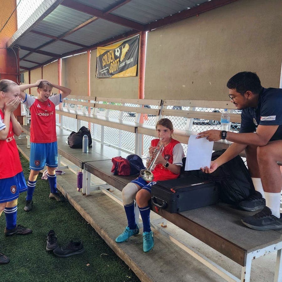 Players and a coach at the side of the pitch between drills