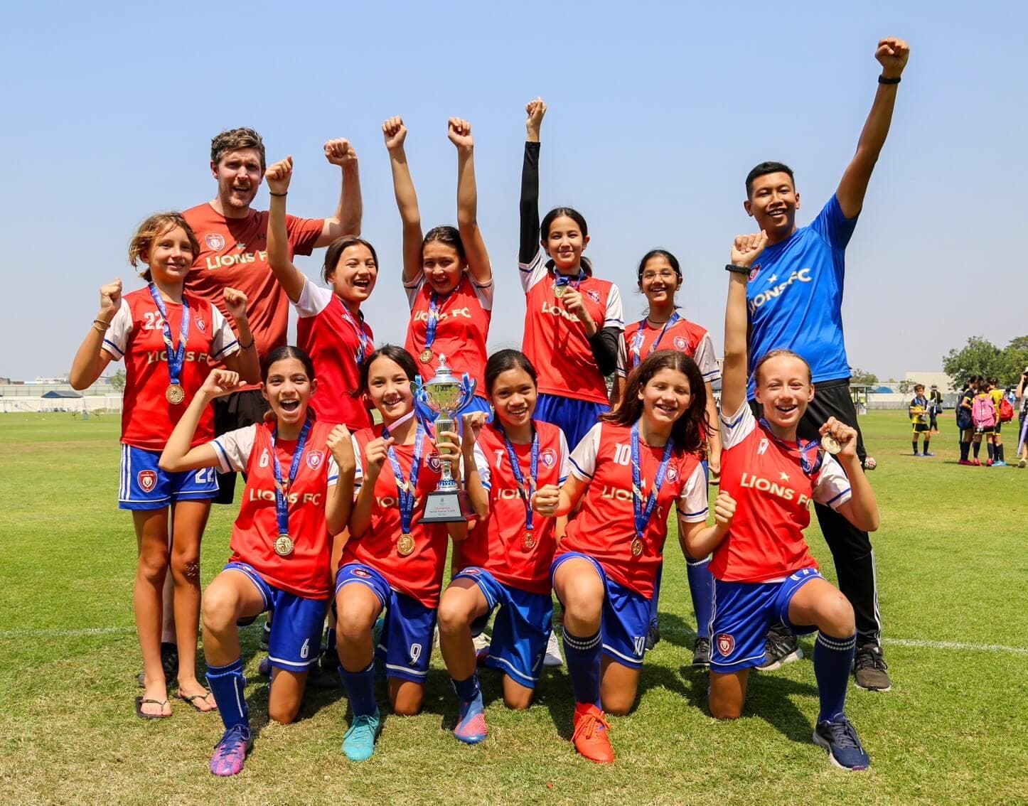 The squad and their coaches celebrating with the cup and their medals after winning the Harrow U13 tournament